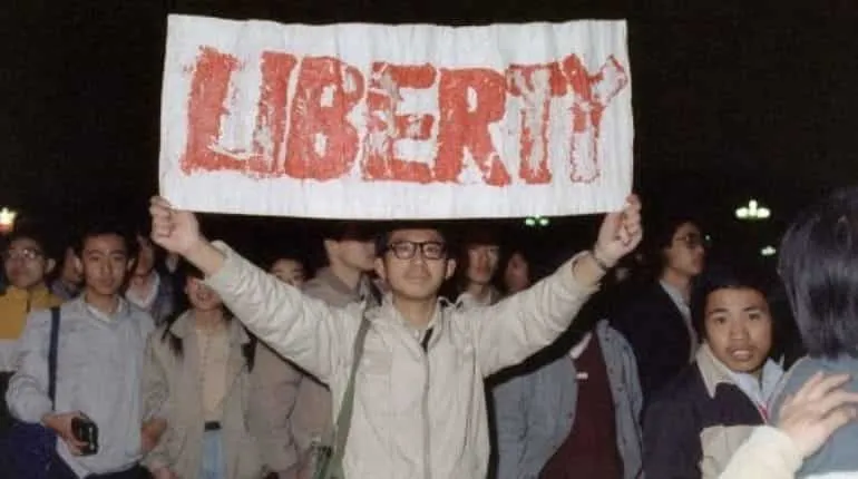 Student displays a banner with one of the slogans chanted by the crowd of some 200,000 pouring into Tiananmen Square 22 April 1989 in Beijing in an attempt to participate in the funeral ceremony of former Chinese Communist Party leader and liberal reformer Hu Yaobang during an unauthorized demonstration to mourn his death. 